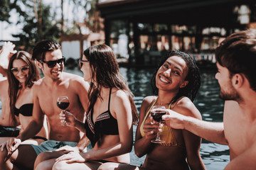Young Smiling Friends Drinking Wine at Poolside