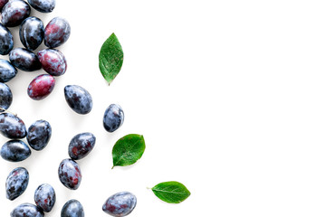 Blue plum for dessert. Purple plum and leaves pattern on white background top view copy space