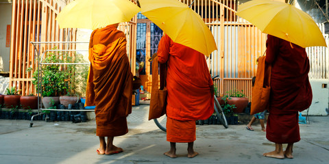 monk with umbrella walking and asking for offering, food