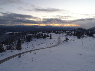 aerial view of fresh snow covered winter forest in high mountains in sunset on christmas eve