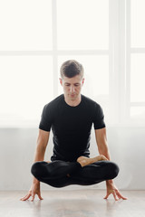Fototapeta premium Young handsome man doing yoga exercises in yoga studio