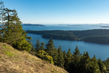 view from the mountain top with ocean and forest covered island under blue sky