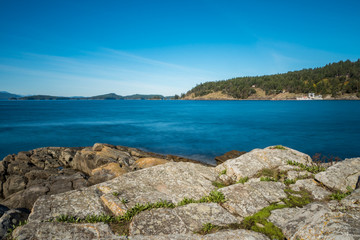 Fototapeta na wymiar view of rocky coast under blue sunny sky with island on the far side