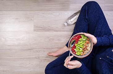Fitness and healthy lifestyle concept. Female is resting and eating a healthy oatmeal after a workout. Top view.