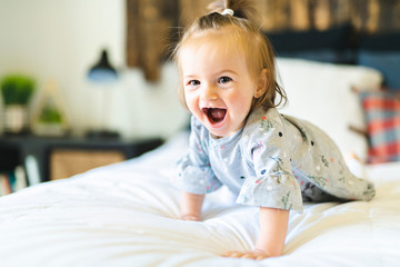 Cute little baby girl on bed at home