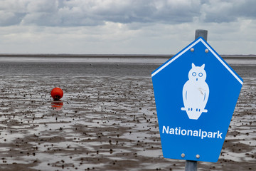 Blue sign of a german national park in front of wadden with german lettering "nationalpark" means national parc