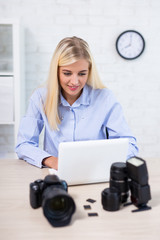 young woman photographer with camera, computer and photography equipment working in office