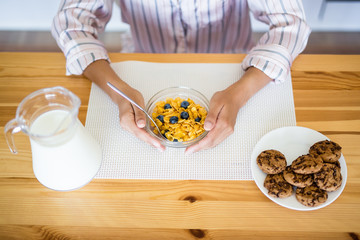 healthy breakfast concept - close up of woman in pajamas eating in the kitchen
