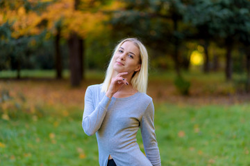 Photo portrait of a beautiful blonde girl in the park on the street in the sunset sun evening.