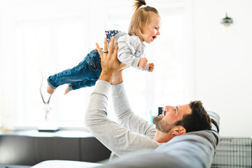 Young father with baby daughter on sofa at home