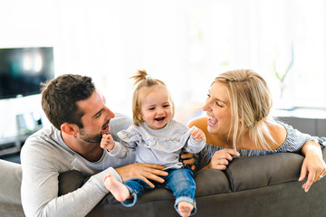 Young family with baby daughter on sofa at home