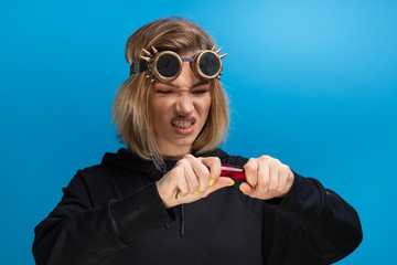 Girl with steam punk glasses tearing a red chilli pepper while looking angry. Portrait shot in...