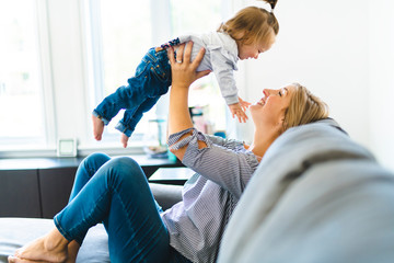 Young mother with baby daughter on sofa at home