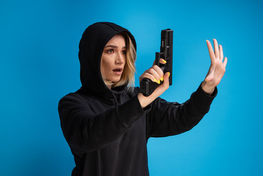 Hooded young girl presenting gun while surrendering. Airsoft game loser