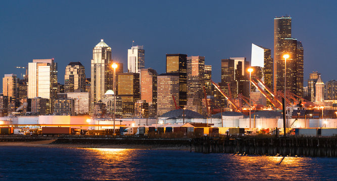 The Seattle Washington Waterfront Glows At Dusk Showing Tanks And Shipping Containers At The Port