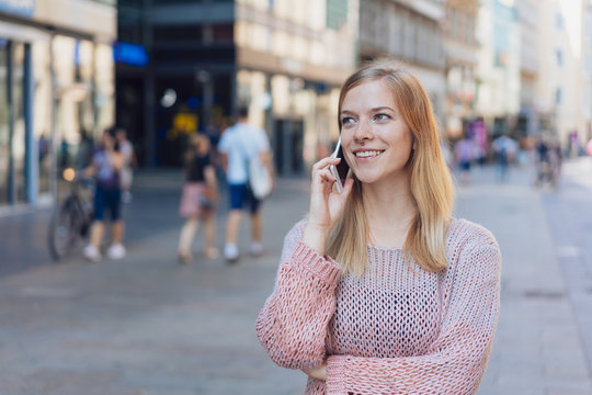 Young woman chatting on a mobile in town