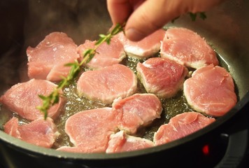 Gebratene Schweinemedaillons in einer Pfanne in spritzendem Fett