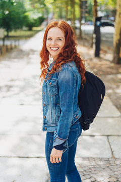 Smiling friendly young redhead woman in a street