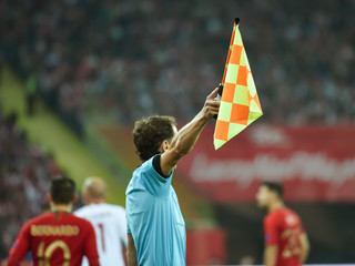 Assistant of football referee with raised flag.