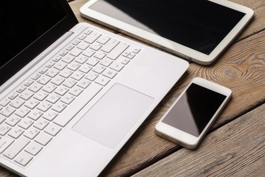 Open laptop with digital tablet and white smartphone close up top view