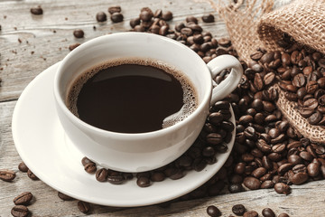 Cup of coffee with beans on table