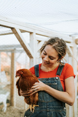 Happy young woman with a brown hen