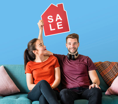 Cheerful couple holding a house sale icon