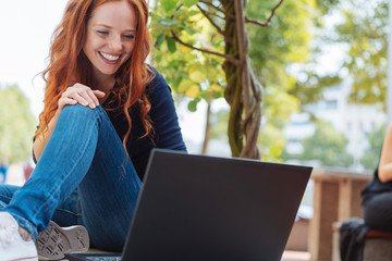 Pretty young woman using a laptop in town