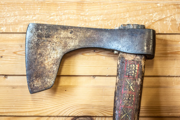 Old Russian historic ax on the background of the wall of a wooden house.