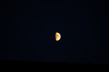 Half moon rising over a roof top early in the evening in southern Germany with mars on the right.