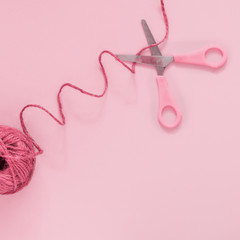 Rosy scissors cut pink thread, pastel background, minimal, art, flatlay Concept - a break between actions, stop