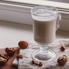 Walnut milk on a beige background, alternative drink, close-up