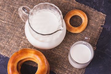 Milk in a jug and a cup with bagels on the table