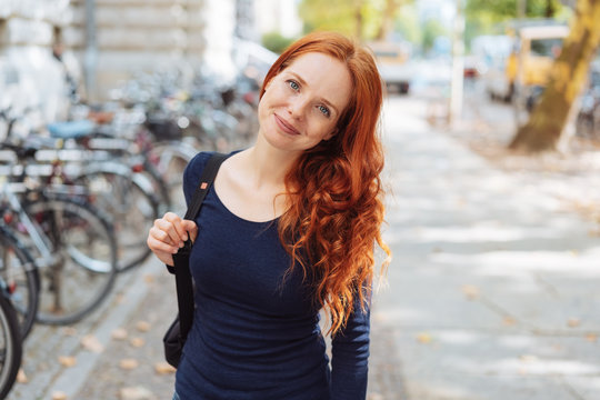Friendly young redhead woman wearing a backpack