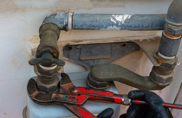Worker with a caliper disassembles a fitting between the pipe and gas meter. Selective focus