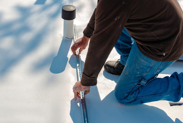Worker with a heat gun is welding PVC sheets for waterproofing a terrace. Selective focus