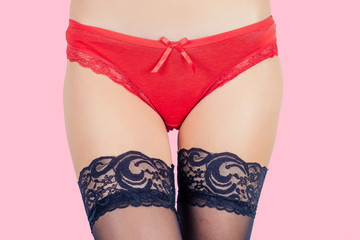 Close-up of sexy red panties on a woman black sexy stockings on a pink background in the studio.The concept of depilation, epilation and removal unwanted hair in the bikini zone