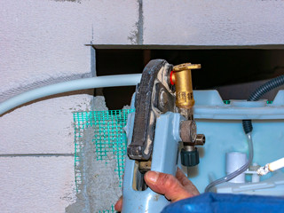 Worker with multilayer pipe presser is assembling the metal bushings of the fittings