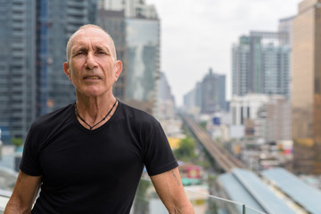 Bald senior tourist man against view of the city in Bangkok Thai