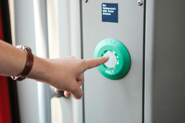 The person presses the stop button in the train. The inscription in German language is translated -...
