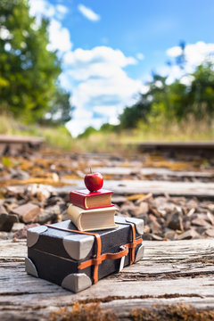 Nostalgic Miniatures Railway Travel Scene / Old railway track through beautiful nature, miniature suitcase, books and apple on heap at vintage railroad sleeper (copy space)