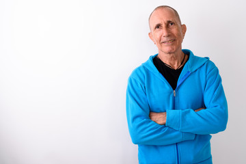 Studio shot of happy bald senior man smiling with arms crossed a