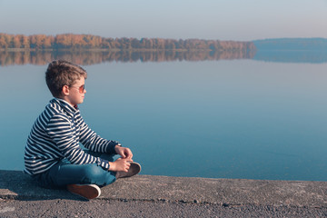 Fototapeta na wymiar Child sitting at waterfront in beautiful autumn light
