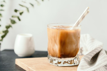 Refreshing iced latte in a glass with straws in a modern kitchen.