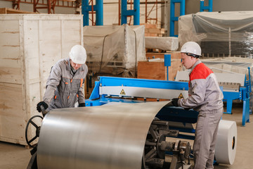 Production of ventilation and drainpipe. Workers adjusts the machine in the warehouse. the production of ventilation and gutters. Tool and bending equipment for sheet metal.