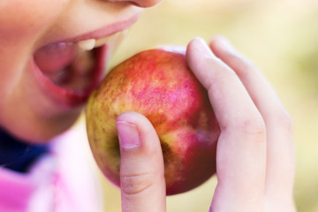 Young girl biting ripe juicy apple_