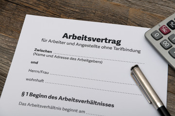 Deutscher Arbeitsvertrag Tarif Vertrag für Angestellte und Arbeitgeber Closeup mit Laptop auf Holz Tisch zum Unterschreiben