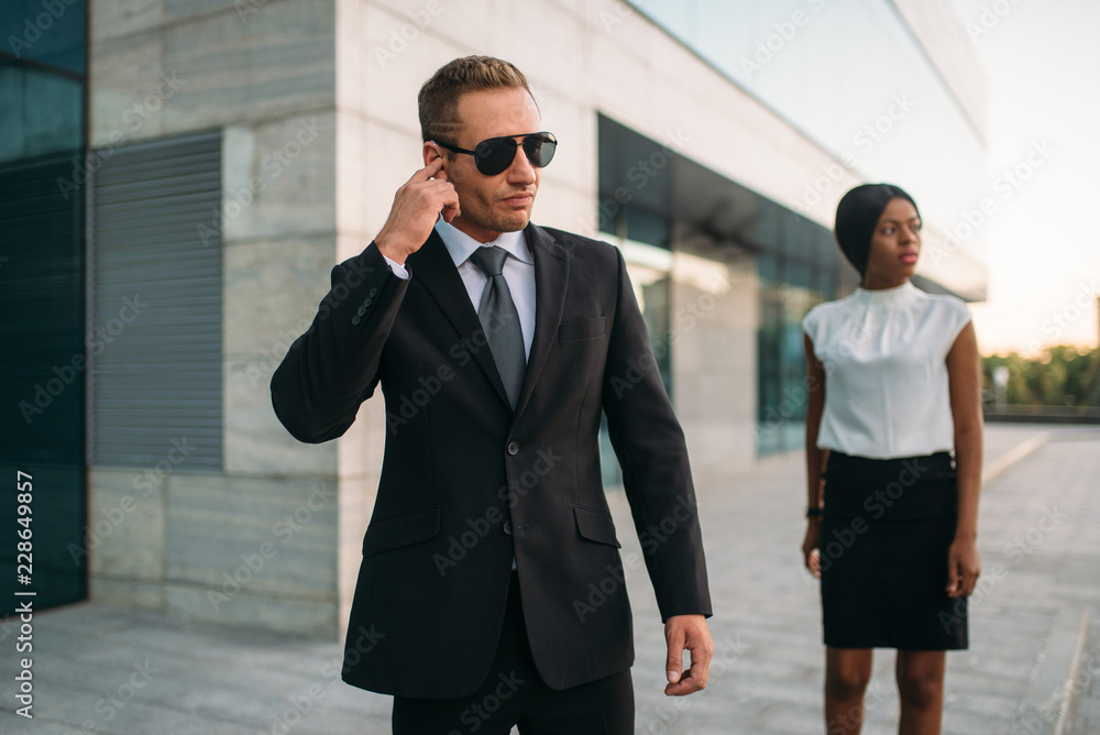 Wall mural bodyguard in sunglasses and black business woman