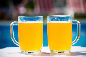 glass of beer near the pool water in the summer on vacation