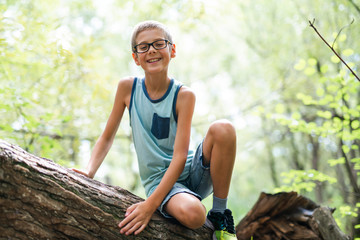 Naklejka na ściany i meble Portrait of a happy young boy outdoors forest